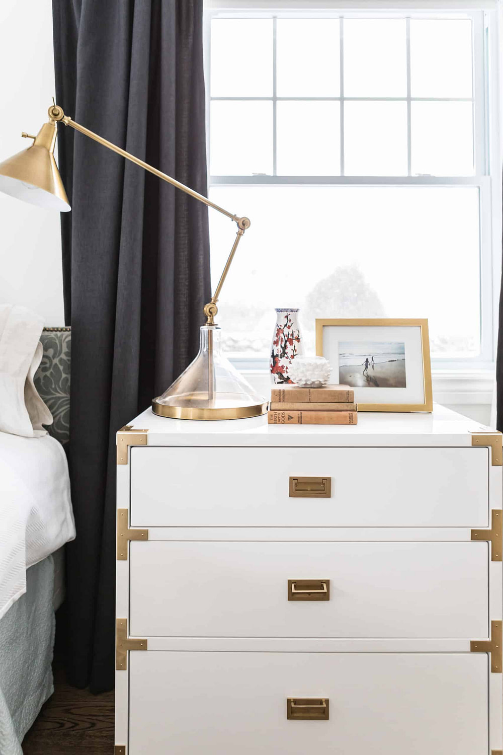 White bedside table with a tall work lamp on it