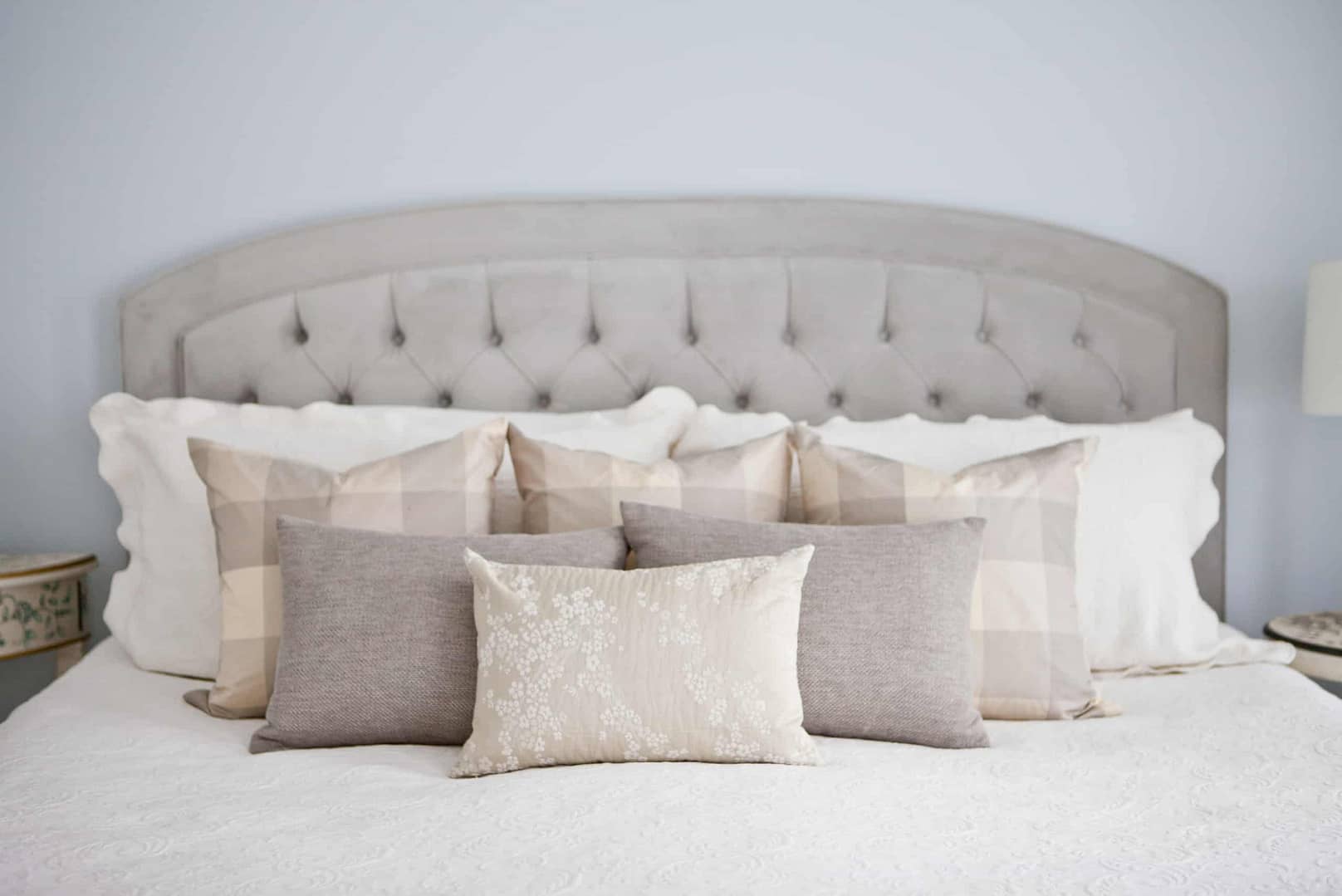 Array of grey and gold pillows on a large white bed